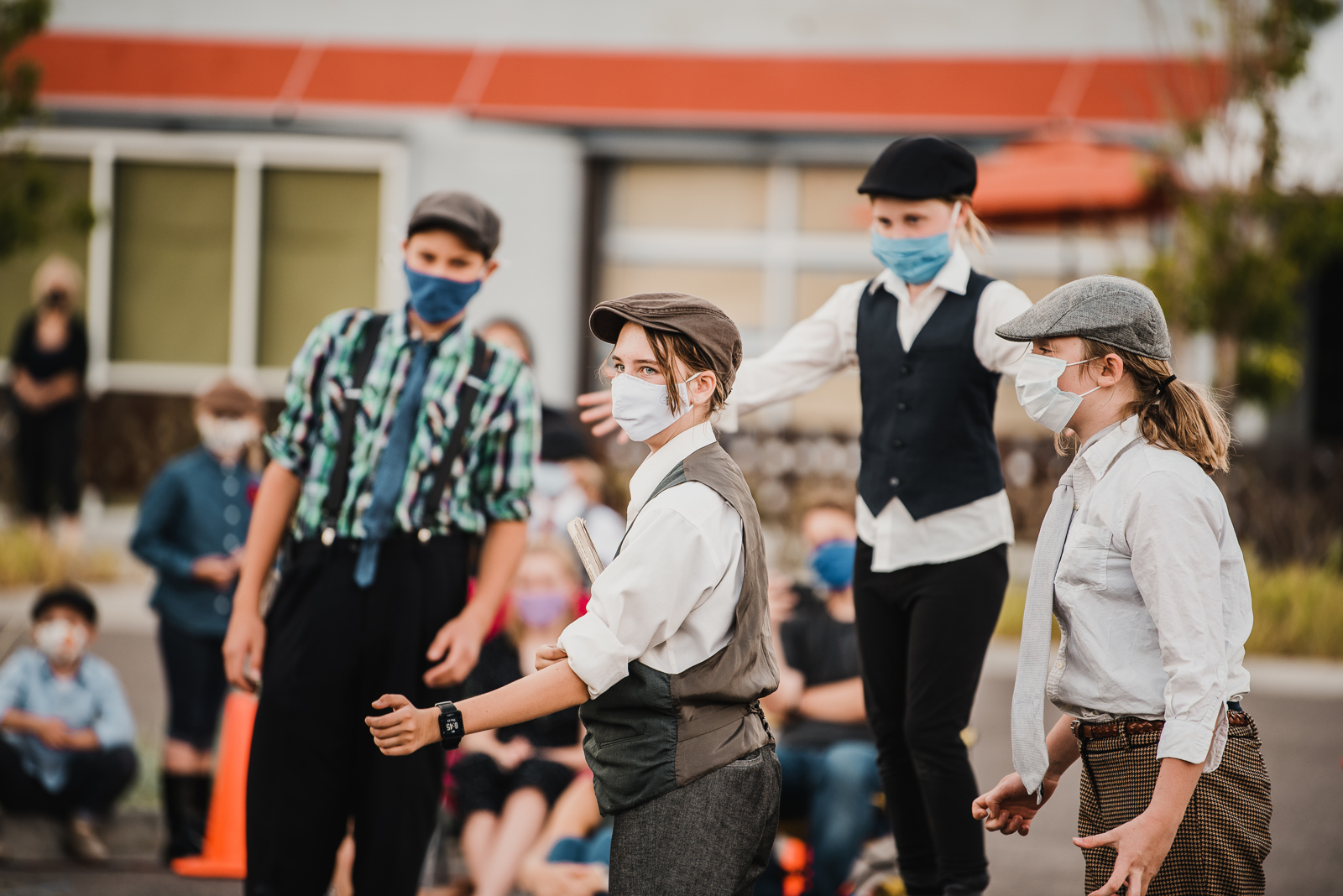 Photo of kids in theatre wearing masks outside in pageboy outfits