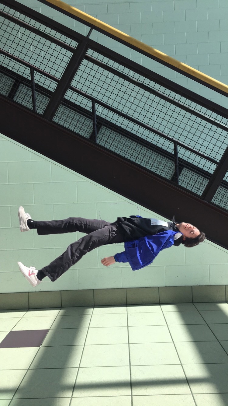 A young man appears to be suspended or falling in an indoor space. 
