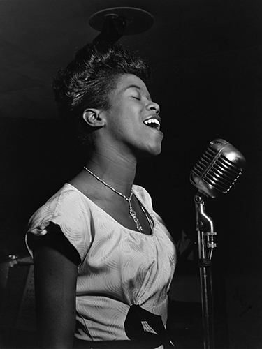 Black and White photo of the singer, Sarah Vaughan. In the 1950's, singing into a mic