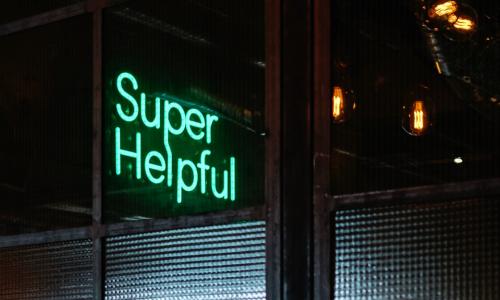 A green neon sign reads Super Helpful