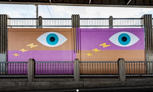 Image of aerosol and acrylic mural painting of wide eyes and lightning bolts, fuchsia and gold rectangular fields