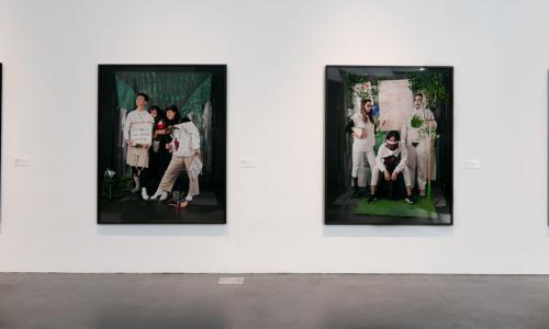 Image of four large blacked framed color prints of students posed in different portrait settings dressed in futuristic ideas with props