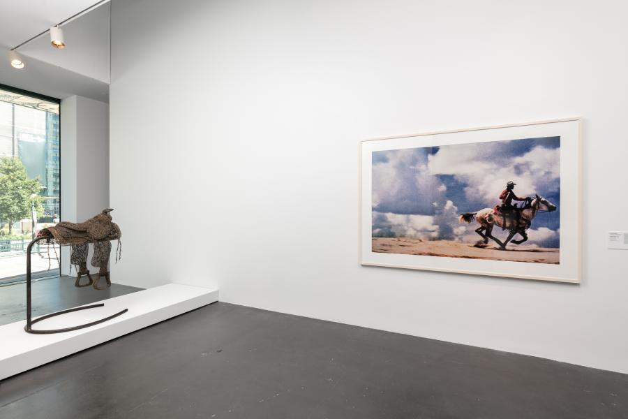 Gallery featuring a saddle and a framed photograph of a cowboy riding a horse.